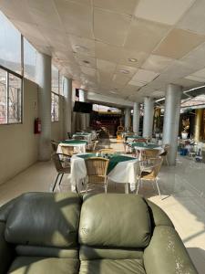 una sala da pranzo con tavoli, sedie e un divano di Hotel Plateros a Cuzco