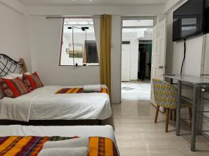 una camera con 2 letti, un tavolo e una scrivania di Hotel Plateros a Cuzco