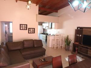 a living room with a brown couch and a kitchen at Aquinini in San José