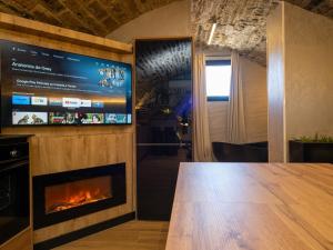 a fireplace in a room with a tv and a table at La Bodega de Casa La Esencia in Aínsa