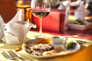 a plate of food and a glass of wine on a table at Ephesia Holiday Beach Club in Kuşadası