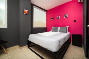 a bedroom with a pink wall with a bed at Adhoc Cintermex in Monterrey