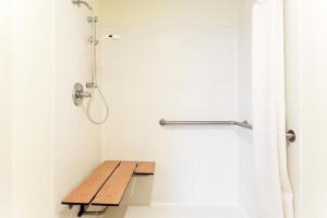 a shower stall with a wooden bench in a bathroom at Western Inn & Suites in Osage