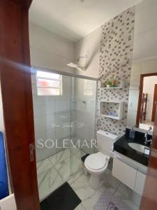 ein Badezimmer mit Glasdusche und Toilette in der Unterkunft Casa de PRAIA Solemar PG 2 quarteirão do MAR in Praia Grande