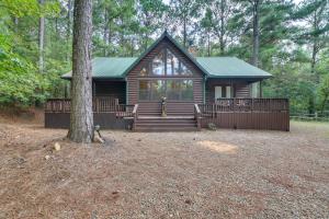 a log cabin with a porch and a tree at Cabin with Hot Tub and Wraparound Deck in Broken Bow! in Broken Bow