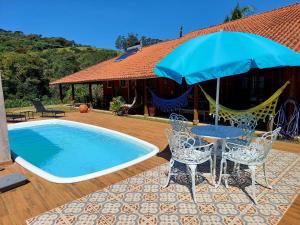 a table and chairs with an umbrella next to a pool at Toca - Bairro Serrano in São Bento do Sapucaí