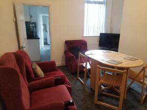 a living room with a red couch and a table at Cosy Home Stay in Etruria