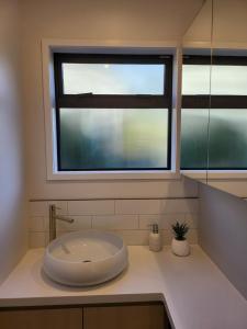 a bathroom with a sink and a window at Pohutukawa Cottage in Ohope Beach