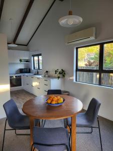 a kitchen with a table with a bowl of fruit on it at Pohutukawa Cottage in Ohope Beach +6 photos