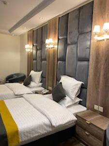 a bedroom with two beds and a wall with two lights at شقق اضواء رفا للشقق المخدومة in Al Kharj