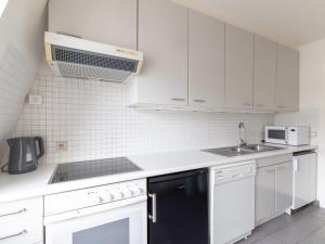 cocina con armarios blancos y lavavajillas negro en Renovated Flat near Beach, en De Haan 32 fotos más