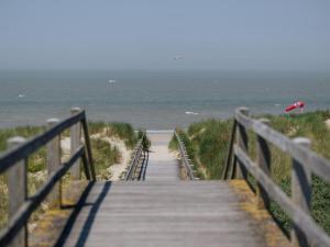 a wooden boardwalk leading to a beach with a red umbrella at Apartment on Belgian Coast with Sea View in De Haan