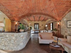 a living room filled with furniture and a stone wall at Hotel Le Pozze Di Lecchi in Gaiole in Chianti