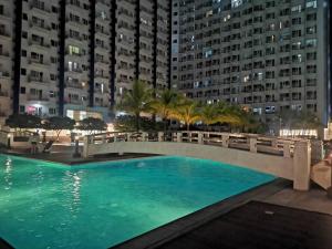 a bridge over a pool at night with buildings at Condo unit open for staycation in Manila