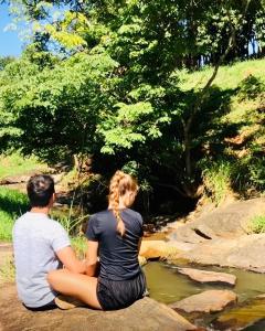 a man and a woman sitting on rocks by a stream at Aconchego no Domo BANHEIRA com AQUECIMENTO 7,5km centro Águas de Lindoia com COM CAFÉ, internet Starlink in Águas de Lindóia +37 photos