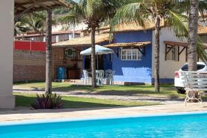 a house with a dog standing next to a swimming pool at Chalé dos Felipe's in Nísia Floresta