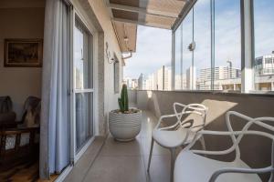 サンパウロにある100 m² com terraço, garagem, A/C | 6x sem jurosのバルコニー(白い椅子2脚、鉢植えの植物付)