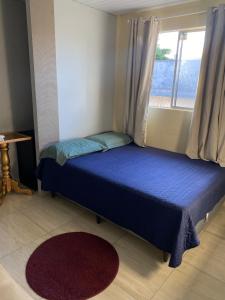 a small bedroom with a blue bed with a window at Quarto - Nosso lar em Natal in Natal