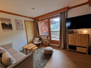 a living room with a couch and a large window at Appartement cosy 6 pers, au pied des pistes avec balcon et WiFi - FR-1-178-386 in Les Bruyères