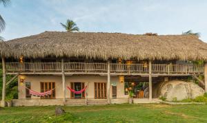 a house with a thatched roof and a large rock at Arrecifes Refugio Natural in Santa Marta