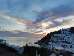 a group of white buildings on a hill next to the ocean at Perigiali Rooms & Apartments Folegandros in Agali