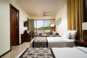 a hotel room with two beds and a balcony at MERUSAKA Nusa Dua in Nusa Dua
