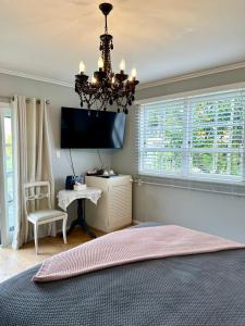a bedroom with a chandelier and a tv and a chair at Bycroft Lodge in Karaka