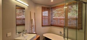 a bathroom with a tub and a sink and a shower at Tawa Whare holiday accommodation in Raglan