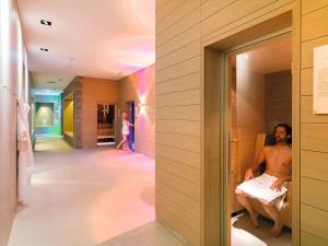 un hombre sentado en una bañera en una habitación en Dolomitengolf Hotel & Spa, en Lavant