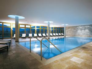 einen Pool in einem Hotel mit Stühlen und Tischen in der Unterkunft Dolomitengolf Hotel & Spa in Lavant