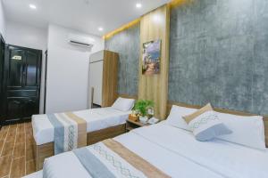a hotel room with two beds and a refrigerator at Peony Hotel in Can Tho