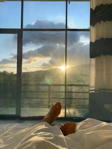 a person laying in bed in front of a window at Ridge Boundary View in Dambulla