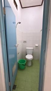 a bathroom with a toilet and a green bucket at Rinjani Homestay in Pangandaran