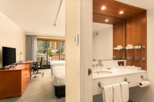 シドニーにあるSydney Harbour Hotelの洗面台、ベッド、鏡のあるバスルーム