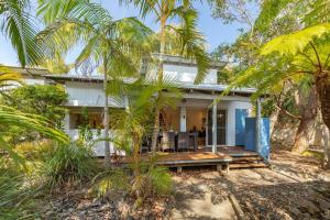 a house on the beach with palm trees at Mobys 29 in Boomerang Beach