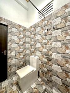 e bagno con servizi igienici in un muro di pietra. di Rustic Cottages Udawalawe a Udawalawe