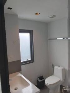 a white bathroom with a toilet and a window at Large Corner Apartment 1BR - NV-207 in Ban Klang
