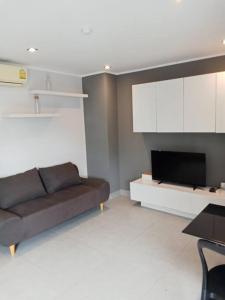 a living room with a couch and a tv at Large Corner Apartment 1BR - NV-207 in Ban Klang