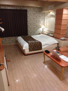 a bedroom with a large bed and a table at HotelおとぼけビーバーPREMIUM in Himeji