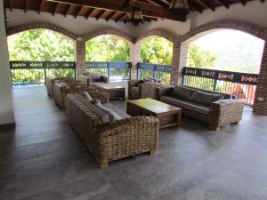 Un patio con sillas y mesas de mimbre y ventanas. en Hotel Aguatur, en Cocorná