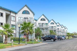 a building with cars parked in a parking lot at Plantation West Condos in Gulf Highlands