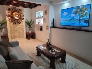 a living room with a couch and a tv on a wall at Auroras in Lagos de Moreno