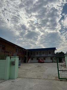 a building with a car parked in a parking lot at 5 Minutes Airport Lodge in Kampong Patagas