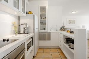 Una cocina blanca con gabinetes y electrodomésticos blancos. en Picture Point 2 - 500m to Hastings St & Noosa Beach, en Noosa Heads