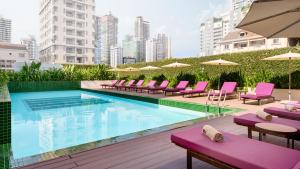 a swimming pool with pink chairs and umbrellas at Baitong Hotel & Resort Phnom Penh in Phnom Penh