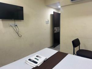 a room with a bed and a tv on the wall at Hotel Vaithi Residency - Andheri West in Mumbai