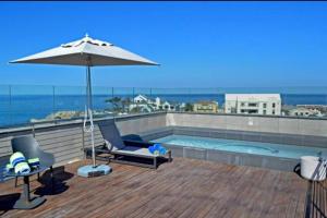 a swimming pool with an umbrella and two chairs and an umbrella at Hermanus Waterfront Apartment 12 in Hermanus