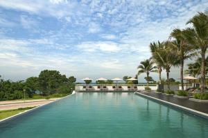 a large swimming pool with palm trees and umbrellas at The Westin Desaru Coast Resort in Desaru