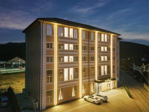 古拉哈莫卢洛伊Sentir Hotel的两辆车停在大楼前的建筑物