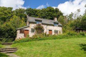 Butterfly Cottage في Wheddon Cross: منزل حجري قديم على تلة مع ساحة